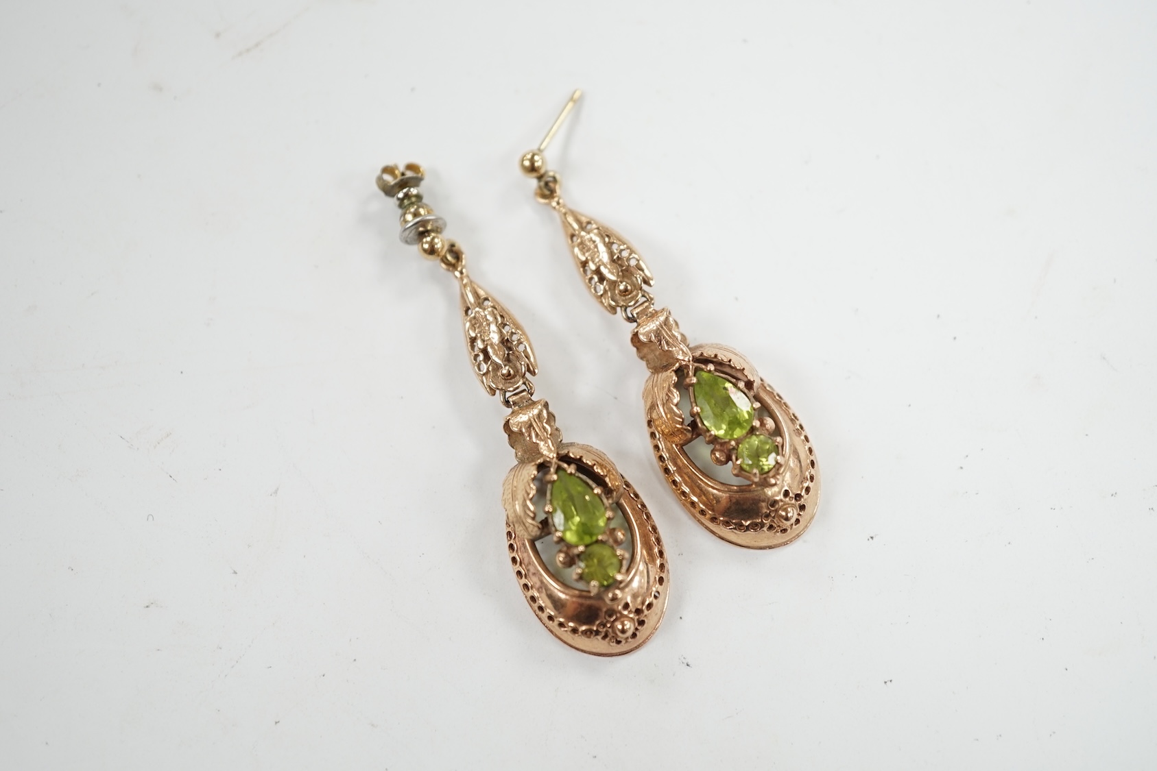 A pair of late 19th/early 20th century style yellow metal and two stone peridot set drop earrings, 48mm. Condition - poor to fair